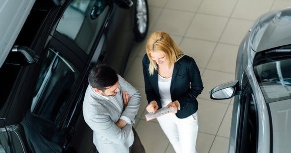 Man talking to woman at car dealership.