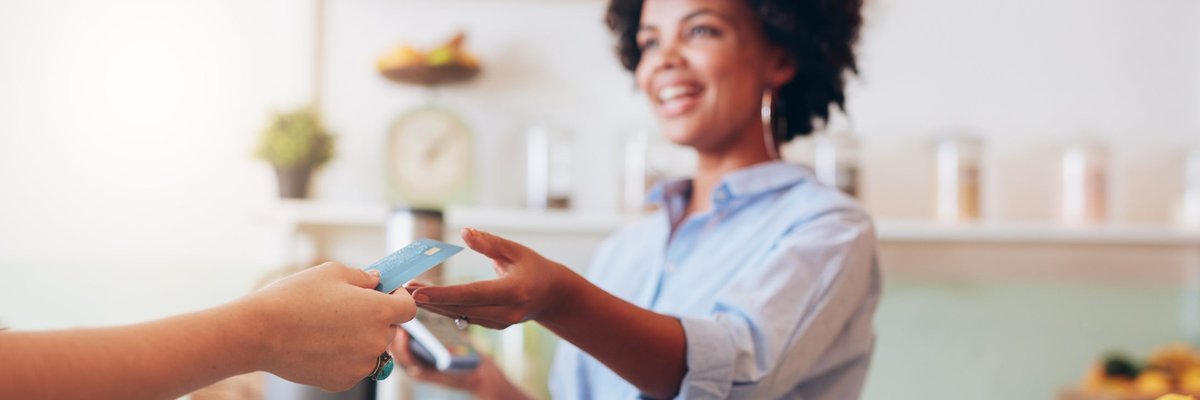 A customer handing their credit card over the counter to the cashier at a cafe.