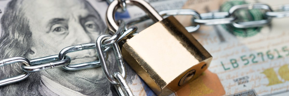 Chain and padlock wrapped around stack of 100 dollar bills.