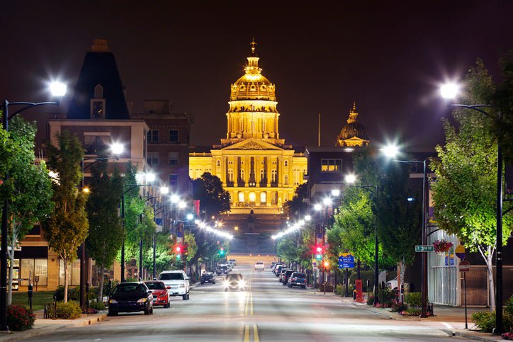 A city street leading up to the Iowa State Capitol building at night in Des Moines.