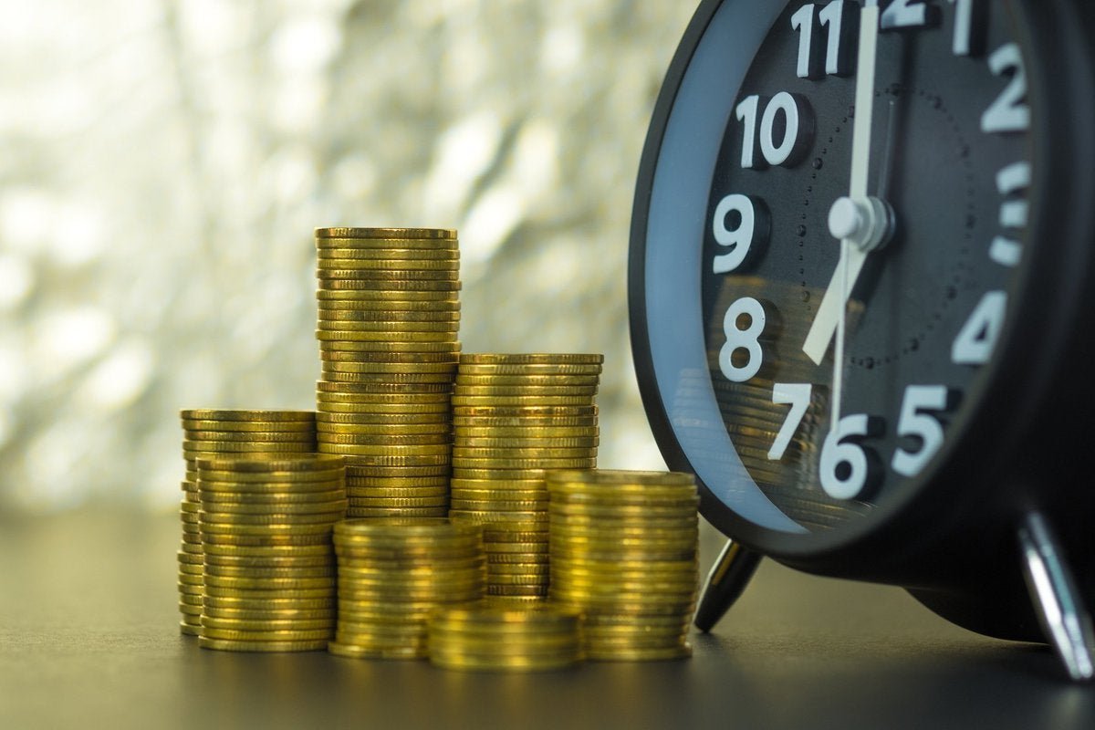Close-up on stacks of coins sitting next to a clock