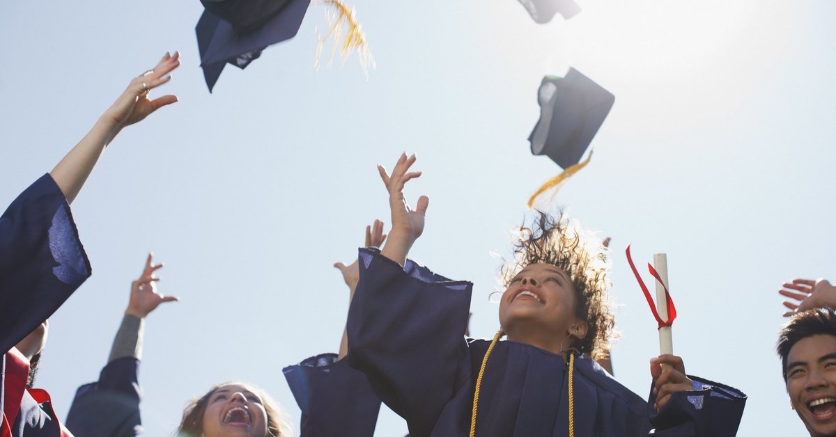 College graduates throwing mortarboards into the air.