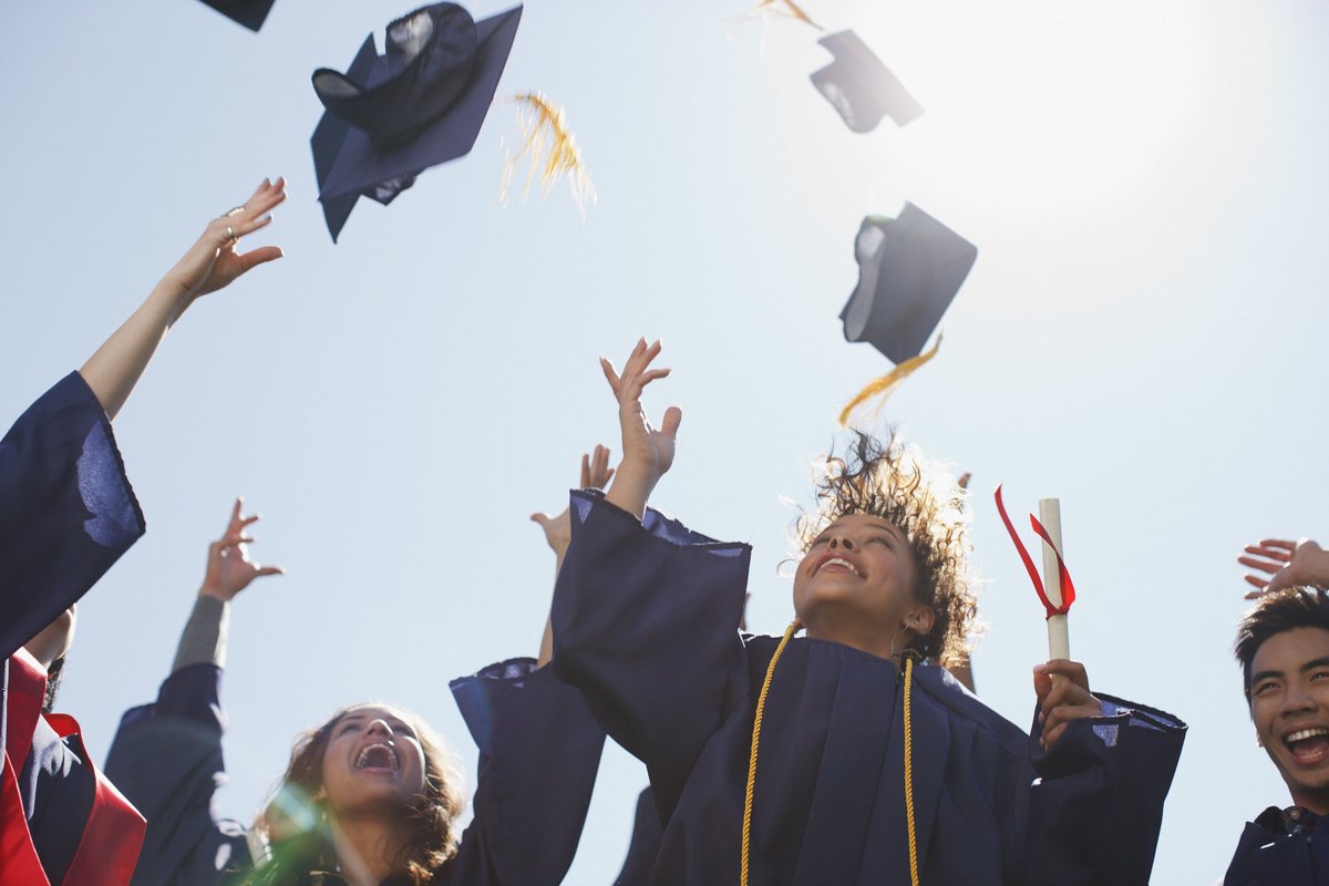 College graduates throwing mortarboards into the air.