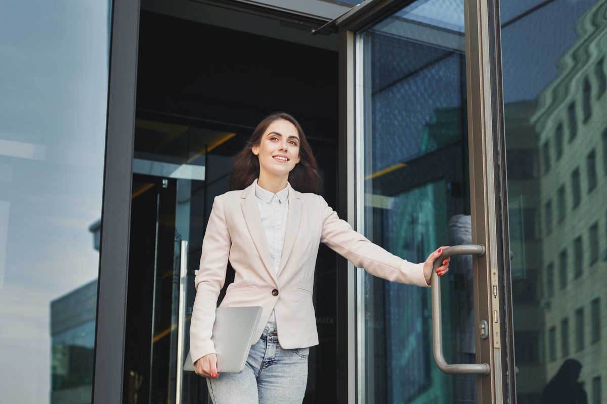 smiling woman walking confidently out of building