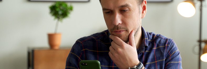 A man looks at his phone, puzzled.