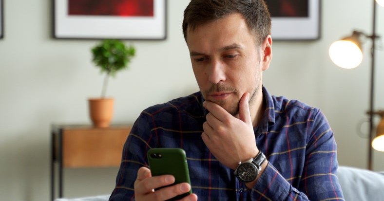 A man looks at his phone, puzzled.