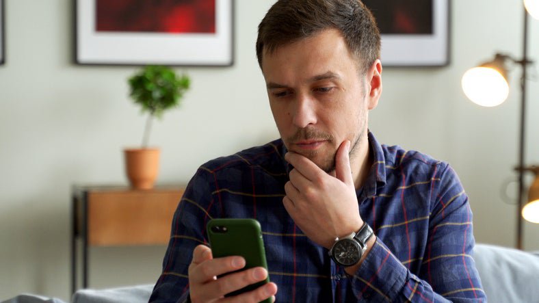 A man looks at his phone, puzzled.