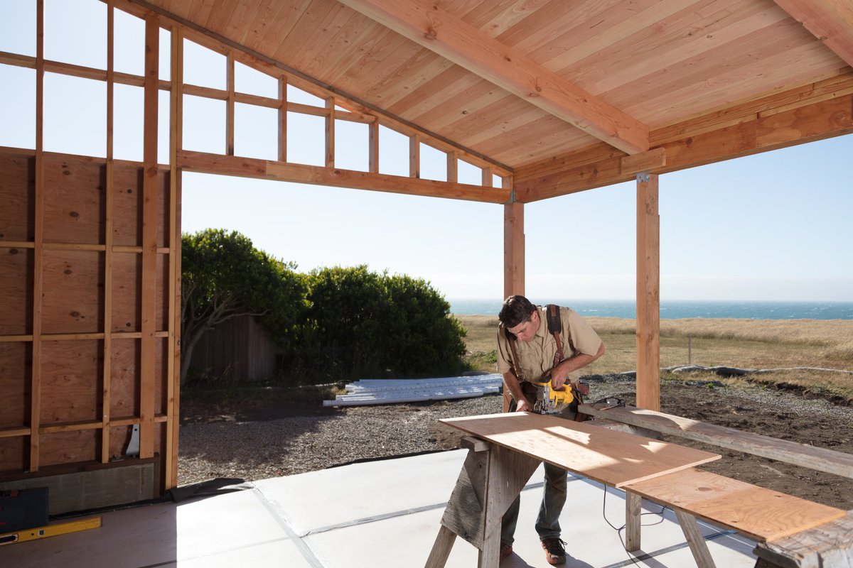 A construction worker sawing wood in a partially built home.