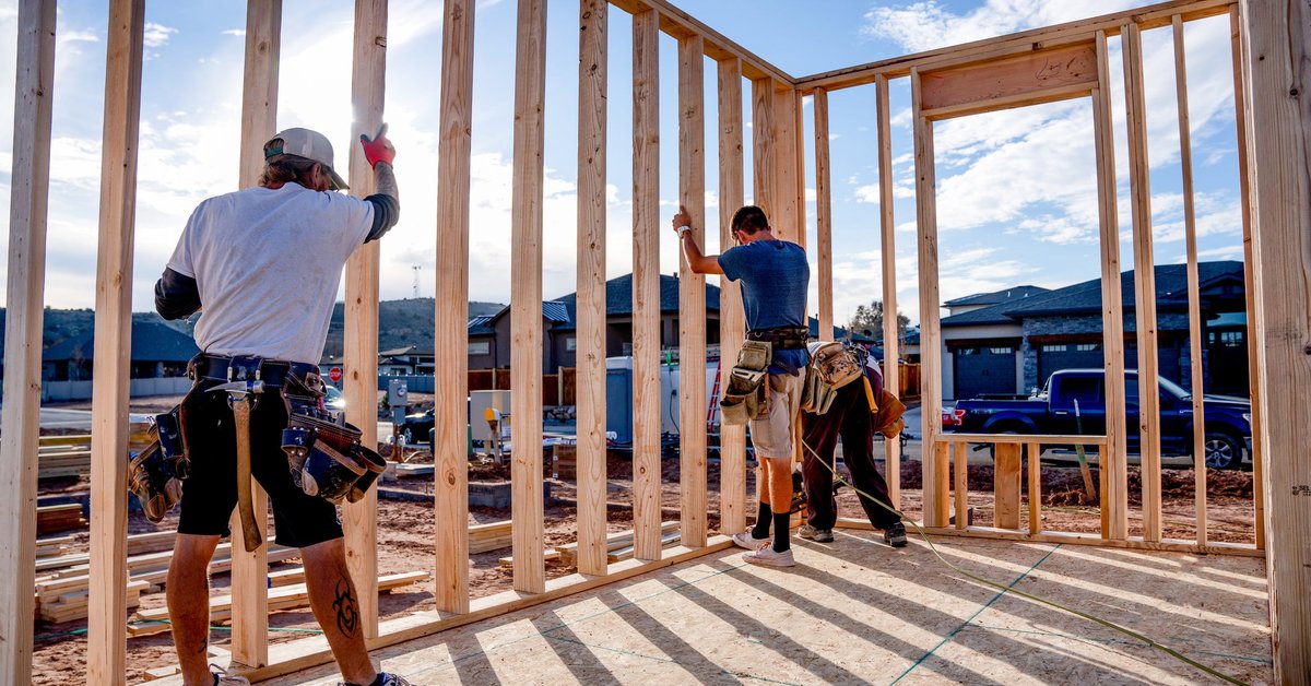 A group of construction workers building the frame of a new house.