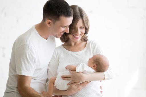 Smiling couple holding a baby. 