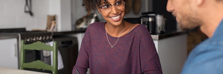 A young woman and man sitting at the kitchen table and looking over paperwork.