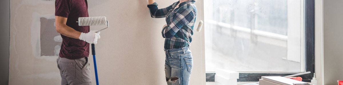 A young couple standing in their home renovation and picking out paint colors.