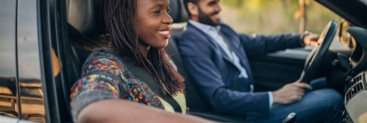 A smiling man and woman driving in a car.