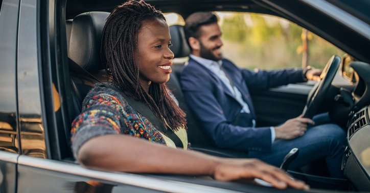 A smiling man and woman driving in a car.