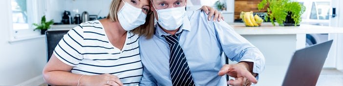 A couple in masks pointing at a computer screen.