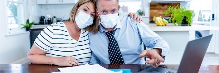 A couple in masks pointing at a computer screen.