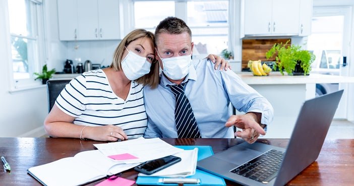 A couple in masks pointing at a computer screen.