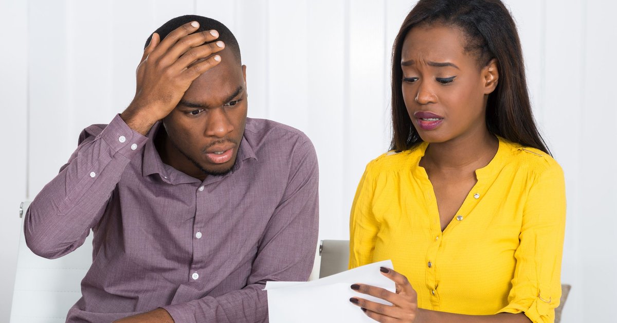 Couple looking at a paper bill together at a table worried