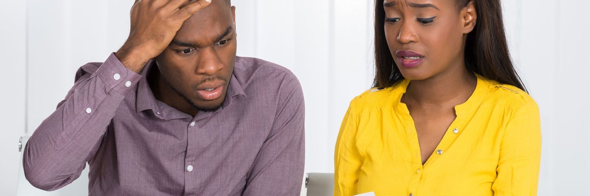 Couple looking at a paper bill together at a table worried