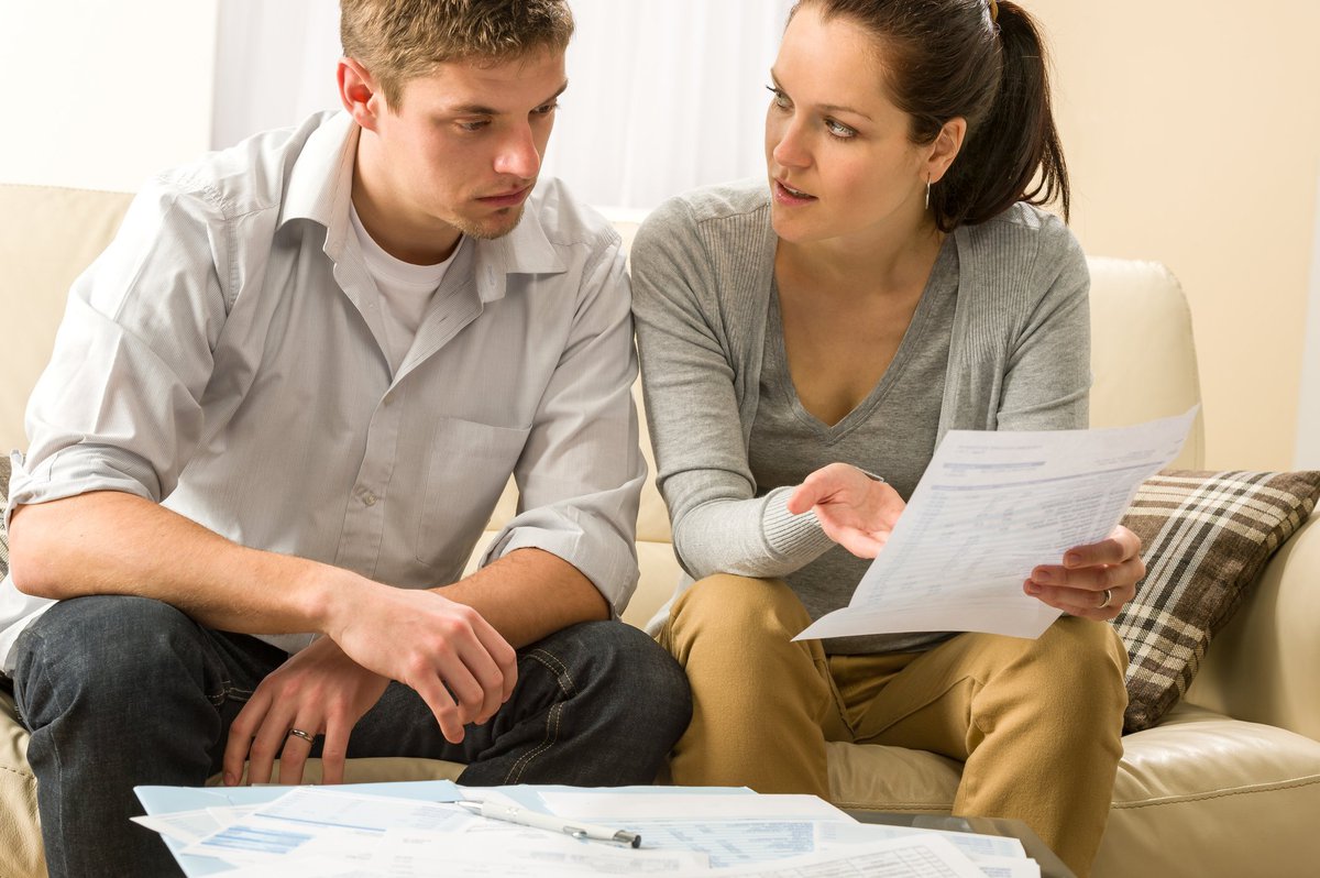 Couple looking at financial paperwork in dismay. 