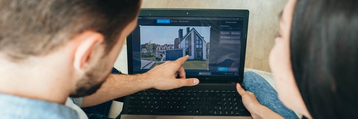 A man and woman sitting next to each other and looking at a house listing on their laptop.