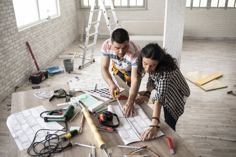 A couple in an empty loft apartment planning out home improvements.