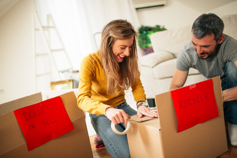 A couple organizing boxes in their home of items to recycle or donate.
