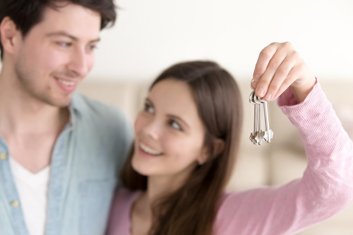 Young couple holds up new house keys