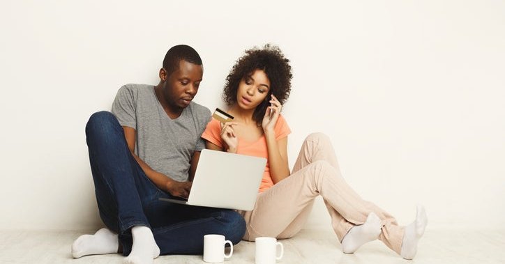 A couple with a credit card, looking at a laptop.