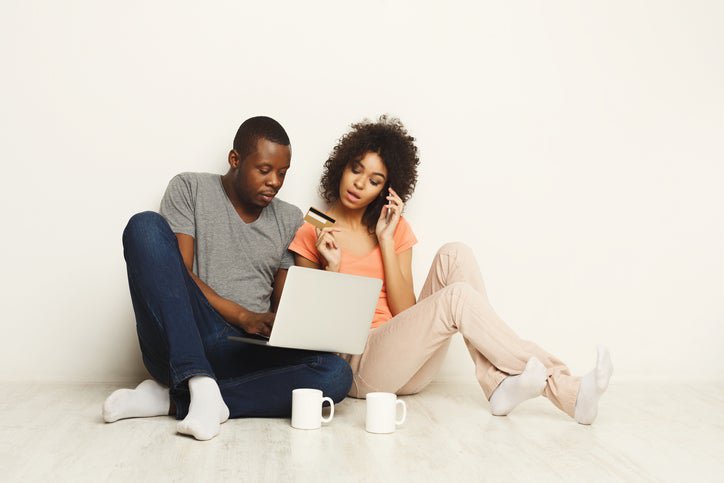 A couple with a credit card, looking at a laptop.