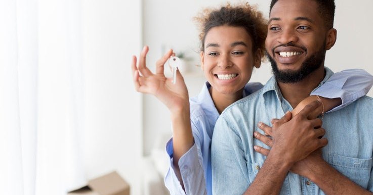 A couple holding up new house keys.