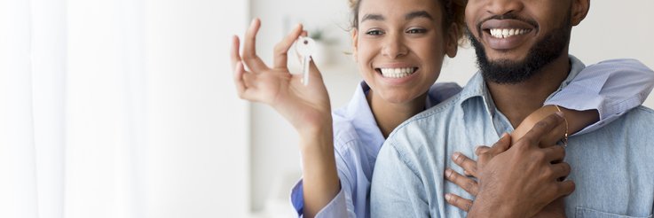 A couple holding up new house keys.
