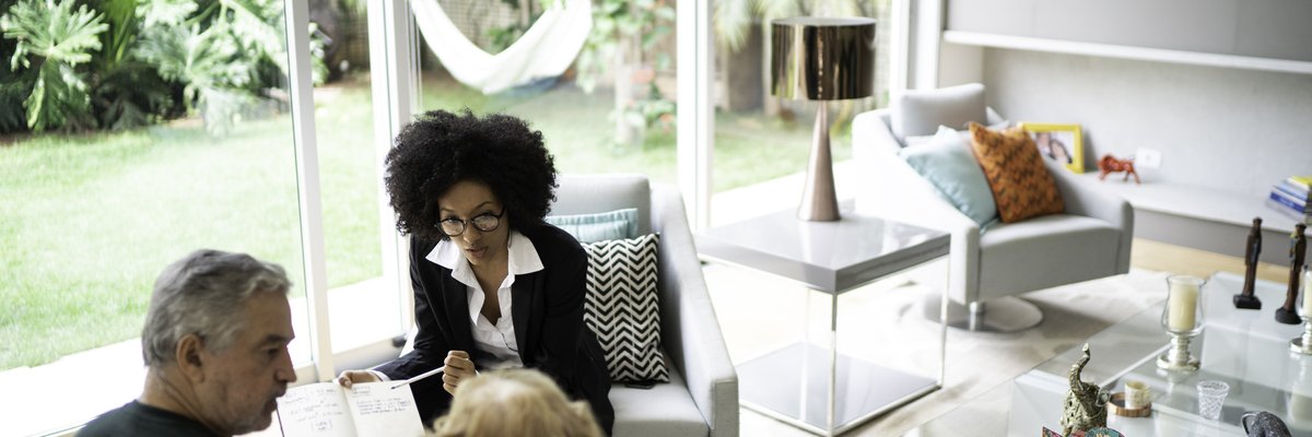 An older couple meeting with their realtor in their living room.