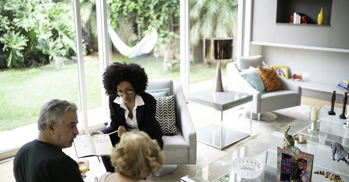 An older couple meeting with their realtor in their living room.