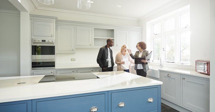 A couple touring the kitchen of a new home with their realtor.