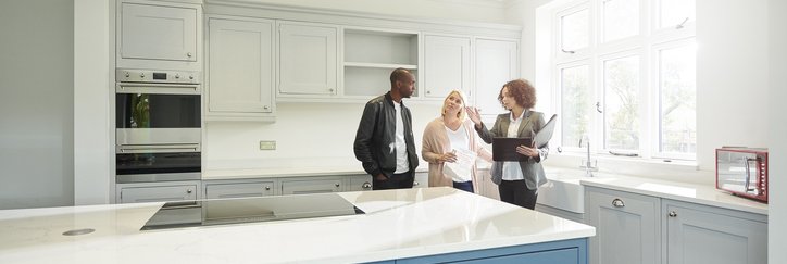 A couple touring the kitchen of a new home with their realtor.