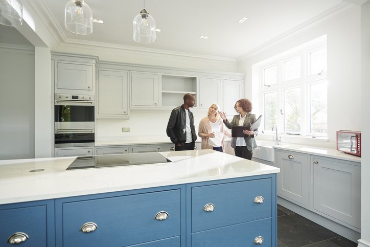 A couple touring the kitchen of a new home with their realtor.