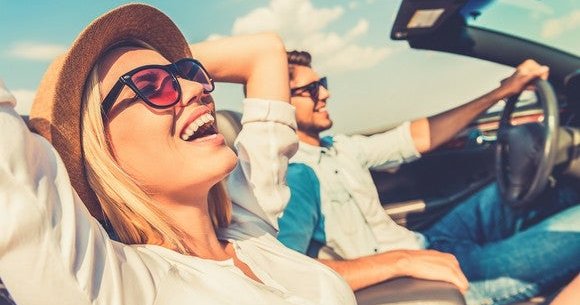 A man and a woman riding in a convertible