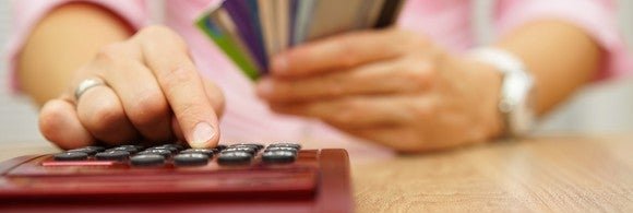 Woman holding credit cards while using a calculator