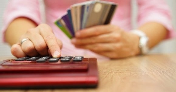 Woman holding credit cards while using a calculator