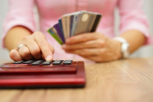 Woman holding credit cards while using a calculator