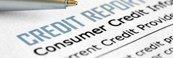 A pen lying next to a consumer credit report.