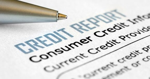 A pen lying next to a consumer credit report.