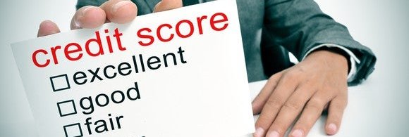 Businessman holding card that says credit score, with categories ranging from excellent to poor.