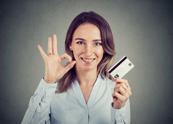 A woman gives the okay sign while holding a credit card.