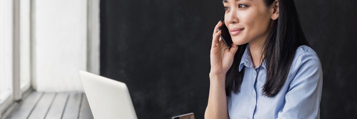A woman holding a credit card and making a phone call.