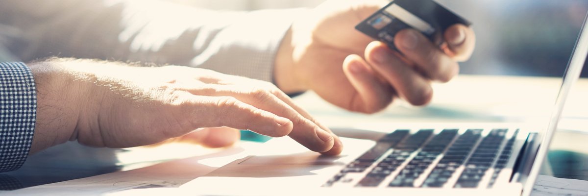 Close up of hands holding a credit card and using a laptop.