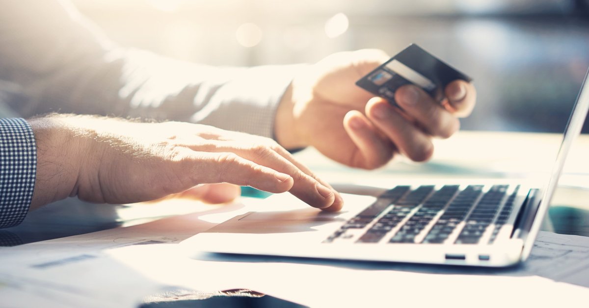 Close up of hands holding a credit card and using a laptop.