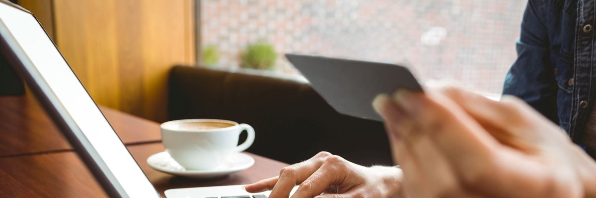 A woman holding a credit card and typing on a laptop.
