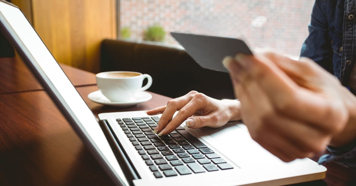 A woman holding a credit card and typing on a laptop.